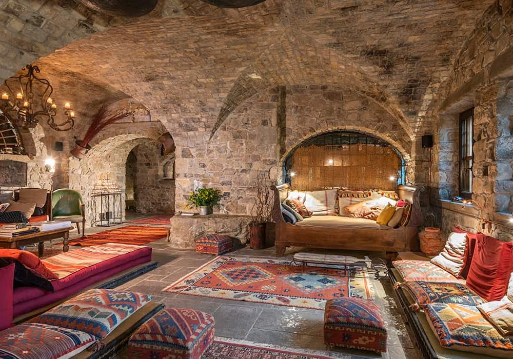 Vaulted stone lounge with kilim rugs, low sofas and colourful cushions