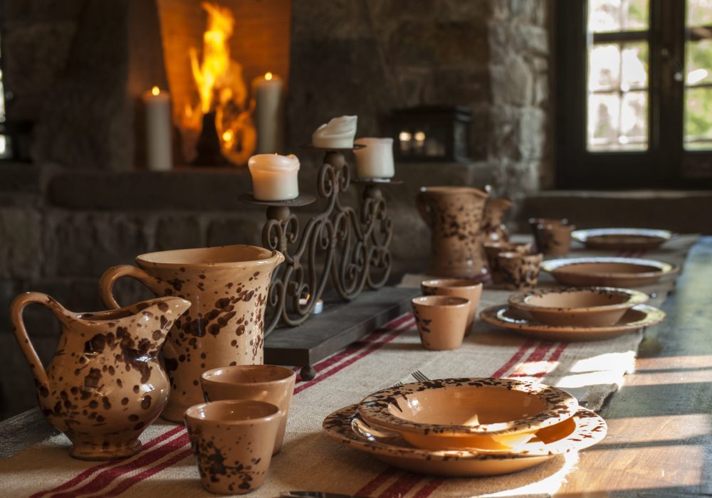 Brocche e ciotole in ceramica artigianale sulla tavola illuminata a candele