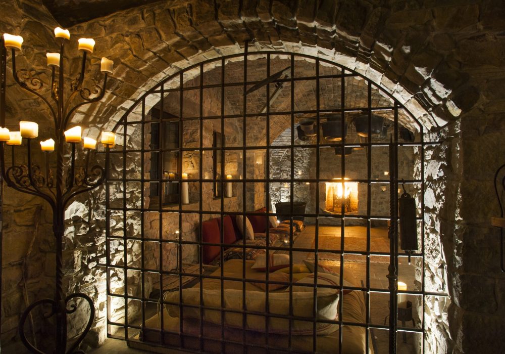 Arco con grata in ferro che si affaccia su una sala illuminata a candele