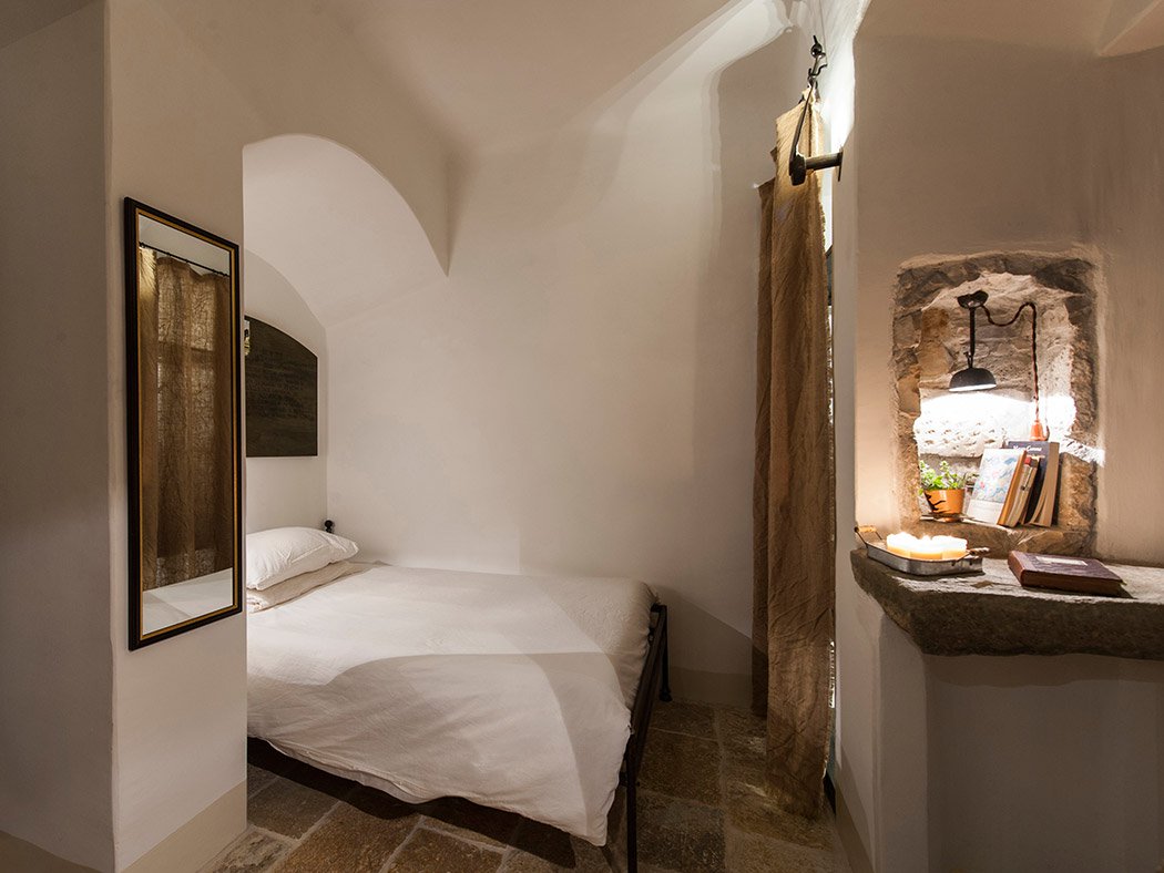 Celluzza Garden, bed set in an alcove and stone niche with books and candles